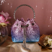 Sparkly purple and blue handbag with decorative handle and keychain on a soft surface.